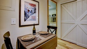 Un comedor con una mesa dispuesta para dos, un cartel enmarcado en la pared y una puerta corredera de estilo granero.