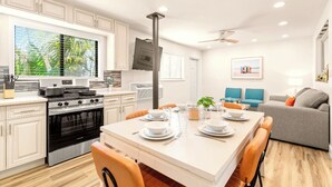 A modern kitchen with white cabinets, a stainless steel stove, and a dining area with a white table set for four. - 🏨 Entire Hotel Takeover! Events, Parties, Heated Pool. Groups up to 46 guests! (Treasure Island)