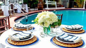 A poolside dining setup with wicker placemats, striped napkins, and a centerpiece of white flowers. - 🏨 Entire Hotel Takeover! Events, Parties, Heated Pool. Groups up to 46 guests! (Treasure Island)