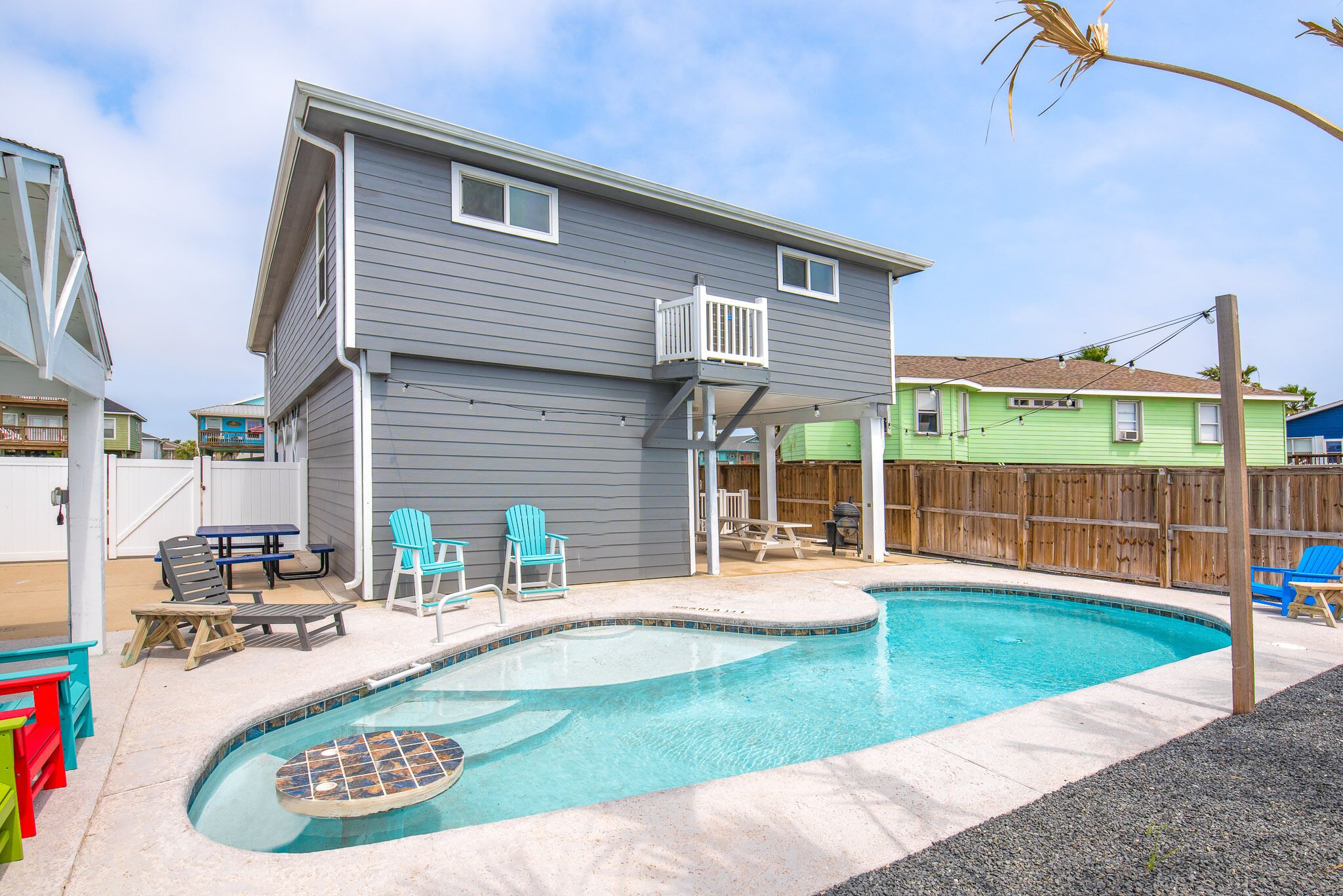 A residential backyard with a swimming pool, a wooden deck, and outdoor furniture.