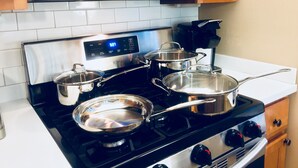 A kitchen with a stainless steel stove, pots, a microwave, and wooden cabinets.