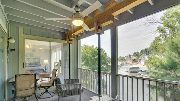 Et værelse med balkon, ventilator og udsigt til en flod og bygninger.