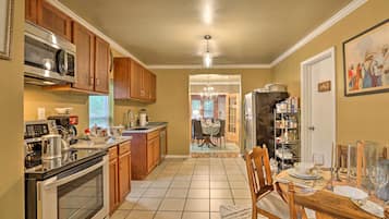 A kitchen with wooden cabinets, a stainless steel microwave, and a dining area with a table set for four.
