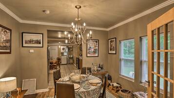 A dining area with a chandelier, framed artwork, and a view of the kitchen.