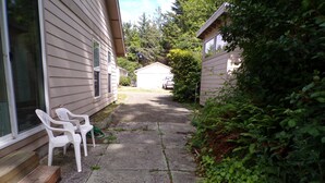 A narrow concrete pathway leading to a house with two white plastic chairs outside. - In the Heart of Netarts (Tillamook)