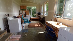 A compact kitchen with a refrigerator, sink, and a dining area with a table and chairs. - In the Heart of Netarts (Tillamook)