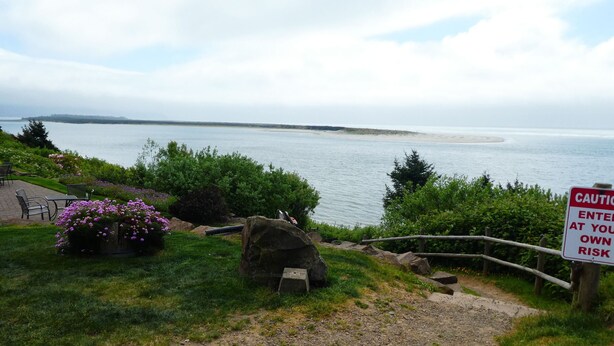 A coastal view with a warning sign, a gravel path, and a seating area with chairs. - In the Heart of Netarts (Tillamook)