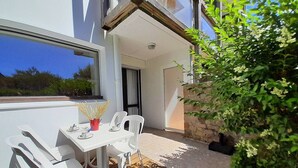Eine Terrasse mit Tisch und Stühlen, einem Blumentopf und Blick auf die Umgebung.