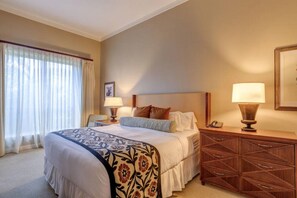 Ein Hotelzimmer mit einem großen Bett, zwei Nachttischlampen, einem Holznachttisch und einem gerahmten Bild an der Wand.