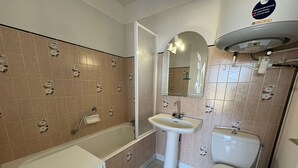 Un baño con bañera, lavamanos, inodoro y espejo.