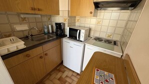 Una cocina compacta con armarios de madera, microondas, cafetera y lavavajillas pequeño.
