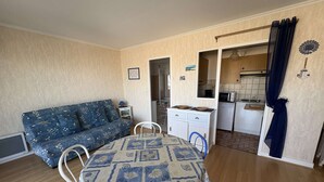 Un espacio habitable compacto con sofá, mesa de comedor y kitchenette.