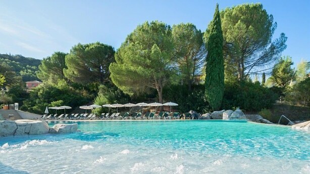 A clear pool with lounge chairs and umbrellas, surrounded by trees and rocks. - Studio Abordable avec Terrasse! (Grospierres)