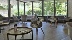 A modern lounge area with sofas and chairs, large windows, and a round table with a menu. - Studio Abordable avec Climatisation | Wi-Fi (Grospierres)