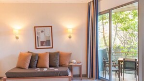 A bedroom with a bed, two wall-mounted lamps, a framed picture, and a sliding glass door leading to an outdoor area with chairs and a table. - Studio Confortable pour la Famille! (Grospierres)
