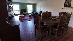 Un coin repas avec une table et des chaises en bois, un téléviseur et une bibliothèque.