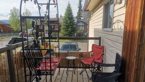 Une terrasse en bois avec un banc, des chaises et une petite table.