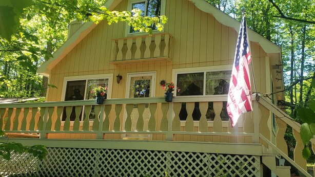 Una cabaña de madera con balcón, una bandera y plantas en macetas.