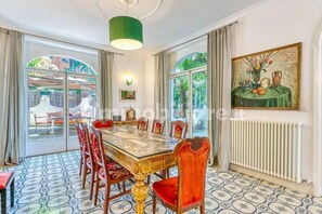 Ein Esszimmer mit einem großen Tisch, Stühlen und einem Gemälde an der Wand.