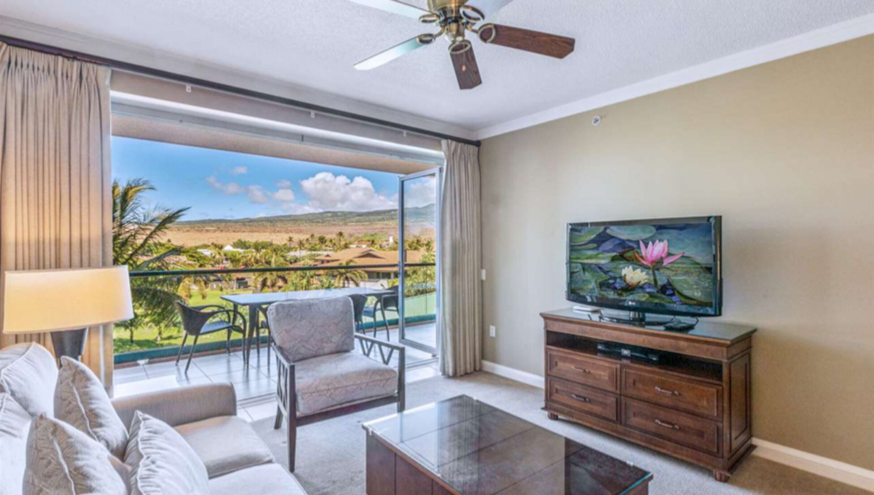 Ein geräumiges Wohnzimmer mit Balkon, Fernseher und Blick auf eine Landschaft.