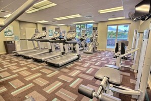 A gym with treadmills, weight machines, and a patterned carpet.