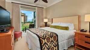 A hotel room with a bed, a television, a desk, and a balcony with a view of a building.