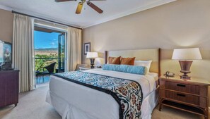 A hotel room with a large bed, two bedside lamps, a TV, a desk, and a chair.