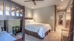 Ein Schlafzimmer mit Etagenbett, einem Einzelbett, einem Deckenventilator und einem Schreibtisch mit Stuhl.