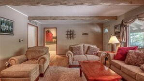 Ein Wohnzimmer mit Holzboden, zwei Sofas, einem Couchtisch und einer Tür zu einem weiteren Raum.