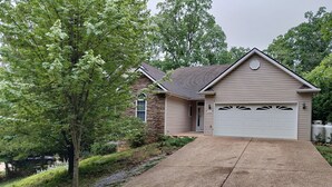 A two-story house with a stone facade, a garage, and a driveway leading to the entrance. - The Great Adventure (McGaheysville)