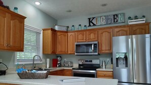 A modern kitchen with wooden cabinets, stainless steel appliances, and a granite countertop. - The Great Adventure (McGaheysville)