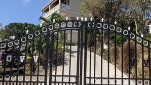 A gated entrance with a vehicle parked inside, leading to a two-story building with a balcony.