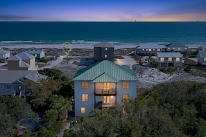 A coastal property with multiple houses, a central building with a balcony, and a view of the ocean.