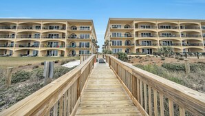 A wooden boardwalk leading to a beachfront hotel with multiple balconies and a clear sky. - Beautiful, FABULOUS Ground Floor Corner Unit @ Adagio E105 (Santa Rosa Beach)