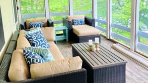 A covered outdoor seating area with wicker furniture, large windows, and a ceiling fan. - Come relax and play! Gameroom, kayaks, paddleboards, fire pit, screen porch (Barnstead)