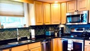 A modern kitchen with granite countertops, stainless steel appliances, and wooden cabinets. - Come relax and play! Gameroom, kayaks, paddleboards, fire pit, screen porch (Barnstead)