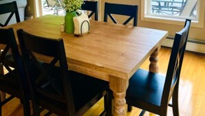 A dining area with a wooden table, black chairs, and a chandelier. - Come relax and play! Gameroom, kayaks, paddleboards, fire pit, screen porch (Barnstead)
