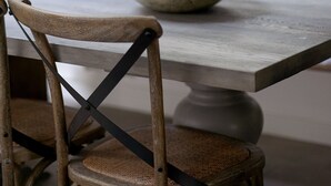 Une table à manger avec un bol de céréales, une chaise en bois et un banc avec des coussins.