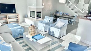 A modern living room with a fireplace, sofas, a coffee table, and a TV. - #1 Location, Spacious Beach House, Steps to Fun (Oceanside)