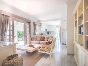 A spacious living area with a sofa, coffee table, and a view of the kitchen.