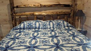 A wooden bed with a blue and white patterned bedspread in a cabin-style room. - What a view of our beautiful Lake Jordan. This cabin is sure to charm you .  (Titus)