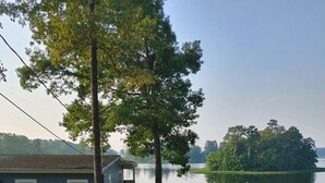A lakeside property with a dock, a covered seating area, and a house with a porch. - What a view of our beautiful Lake Jordan. This cabin is sure to charm you .  (Titus)