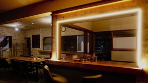 Een bar met een houten toonbank, stoelen en een klok aan de muur.