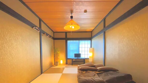 Een traditionele Japanse kamer met tatami vloerbedekking, een lage tafel met kussens en een hanglamp.