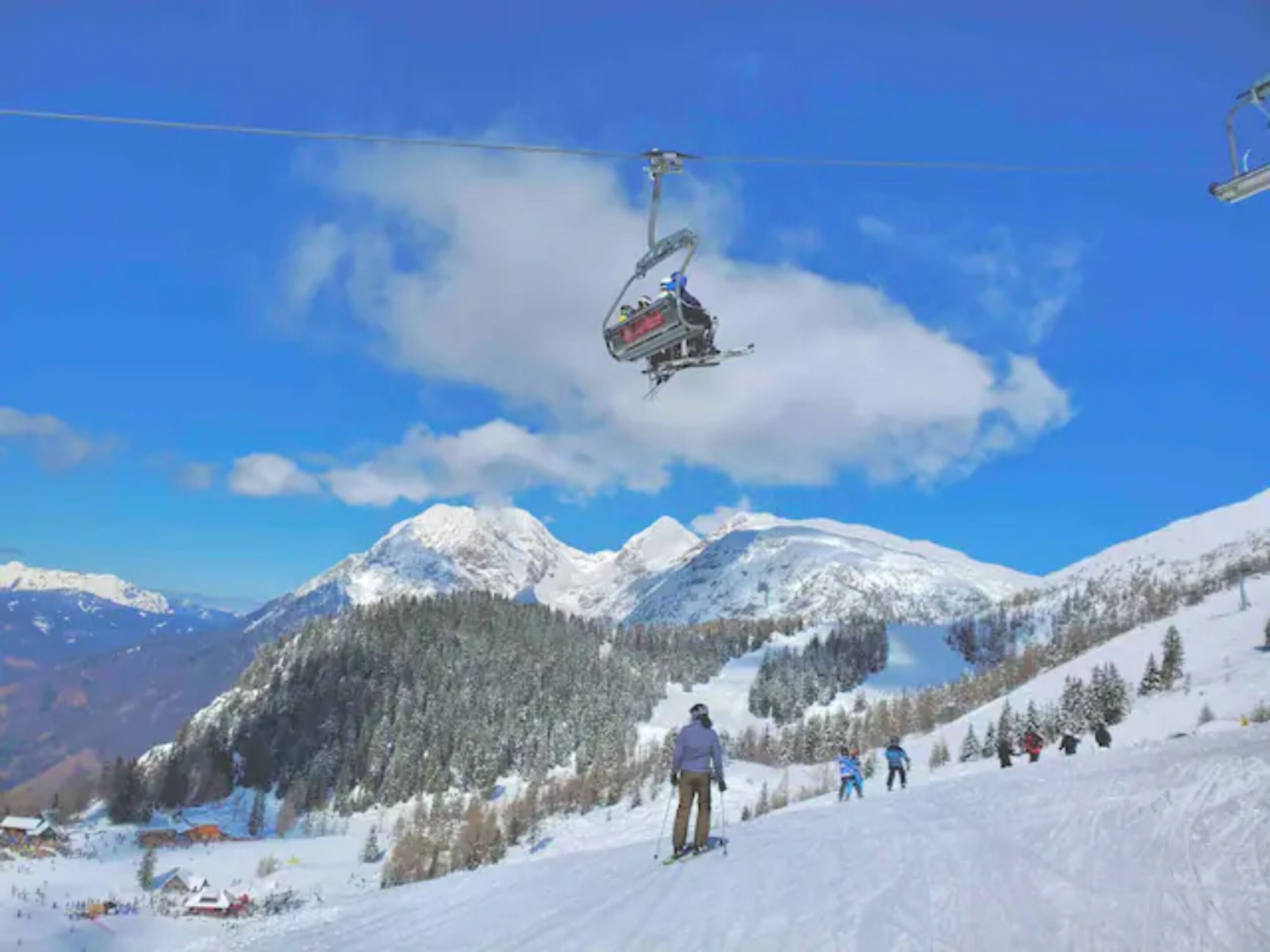 A ski lift with skiers and a mountainous landscape in the background.