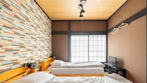 Een kamer met twee bedden, een houten plafond, een metselwerk muur, een raam en een televisie op een dressoir.