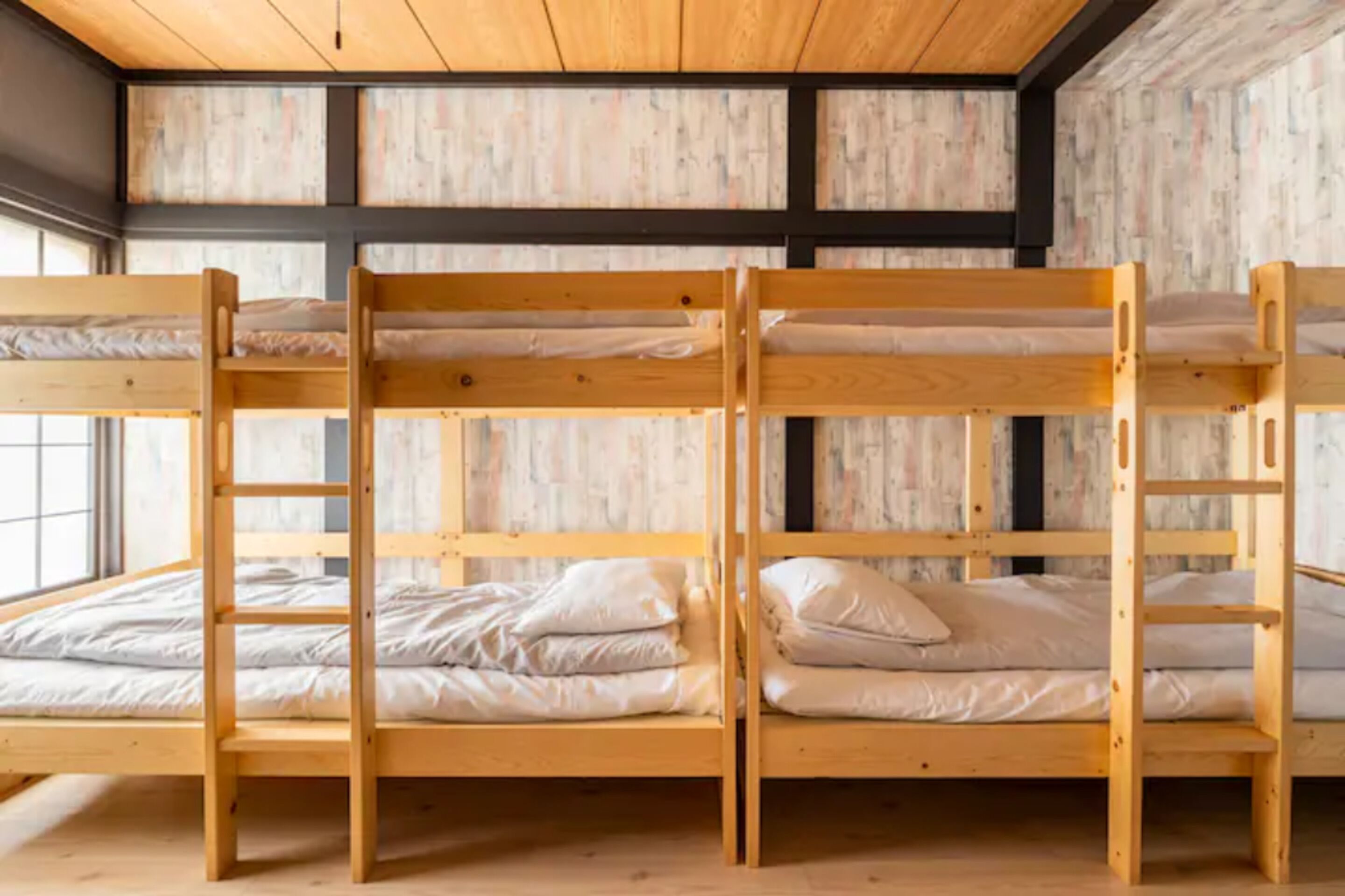 Dormitorio con literas de madera y ropa de cama blanca.