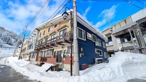 Un immeuble à plusieurs étages, doté d’un balcon au rez-de-chaussée, d’une enseigne indiquant « STARDUST », et d’une rue recouverte de neige.