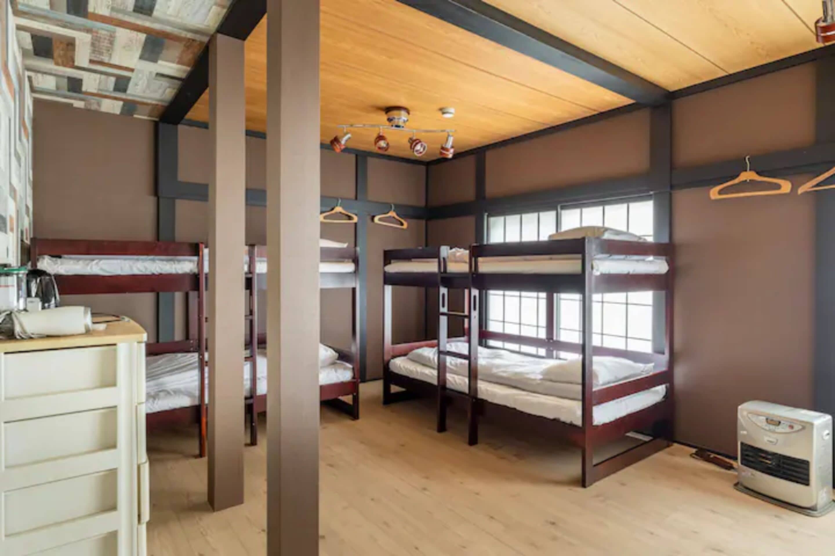Dormitorio con literas, piso de madera, calefacción y ventana.