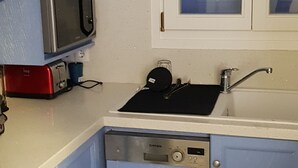 A compact kitchen with blue cabinets, a built-in microwave, a sink, and a dishwasher. - sam29 3-Bed Villa in Monolithos (Monolithos)